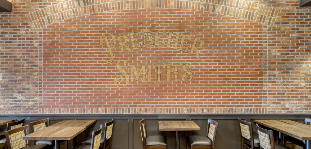 An Image of the brick wall at Preacher Smith's Taproom & Commons. The brick wall showcases the text "Preacher Smith's"