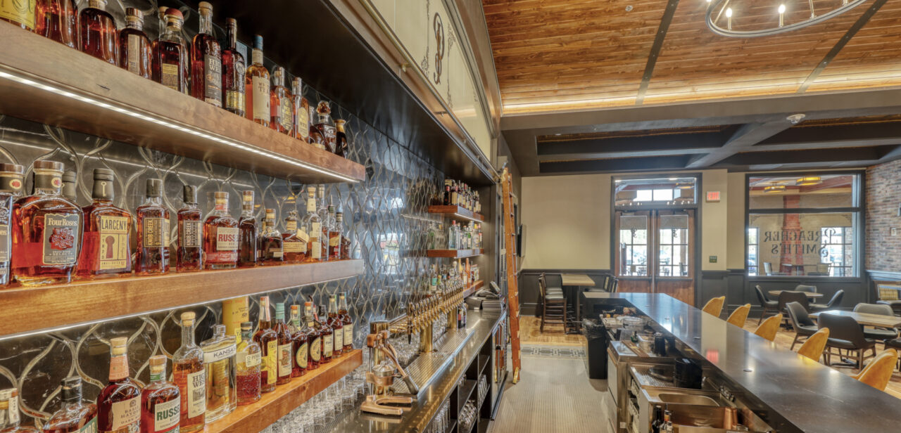 An Image from behind the bar at Preacher Smith's Taproom & Commons. Showcasing the bar seating and liquor offerings.