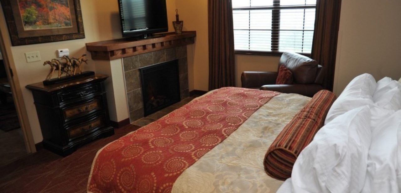 King bed with fireplace inside of the Deadwood Lodge